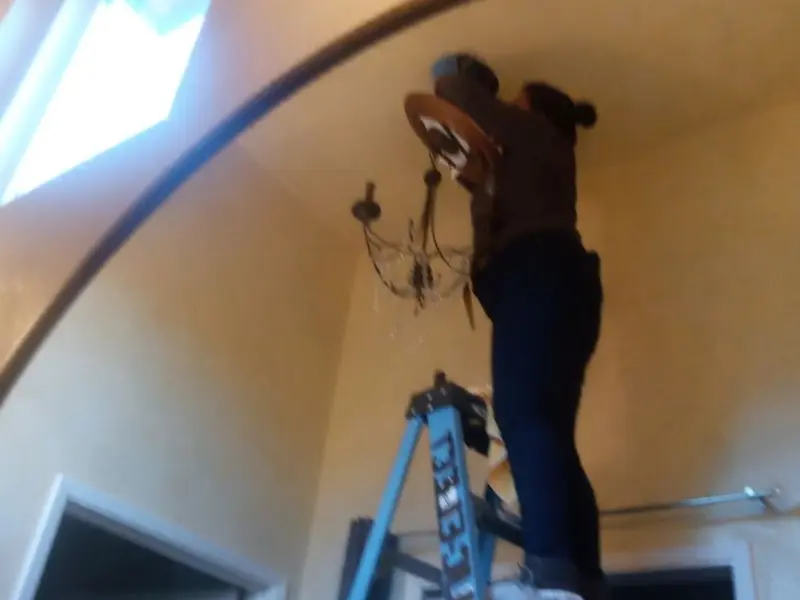 Electrician installing a chandelier in a Saukville residence